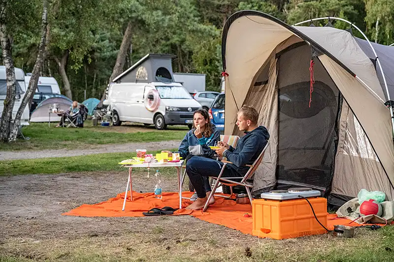 Zwei Camper sitzen vor ihrem Zelt auf dem Campingplatz Thiessow