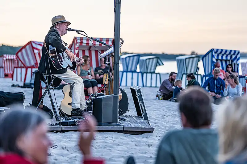 Musiker singt und spielt vor Publikum am Mönchguter Strand