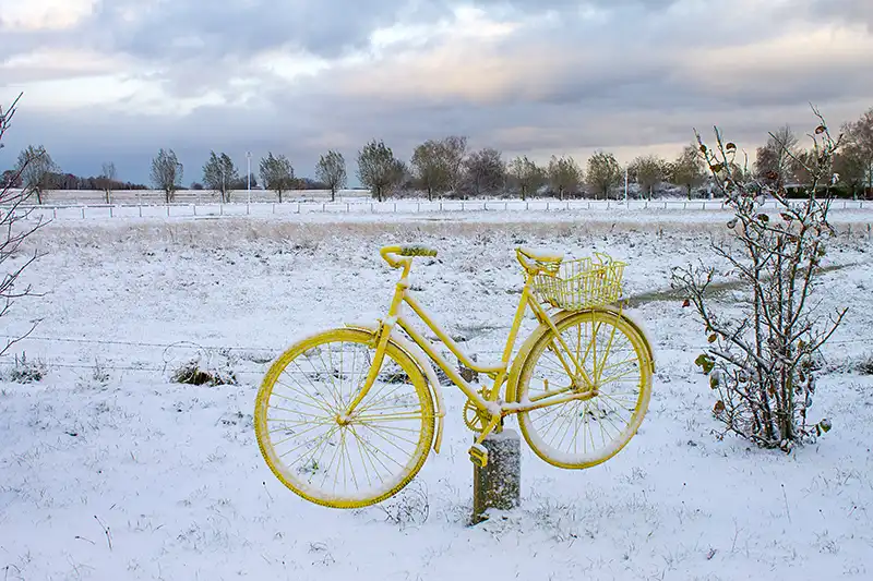 gelbes Fahrrad vor schneebedeckter Landschaft